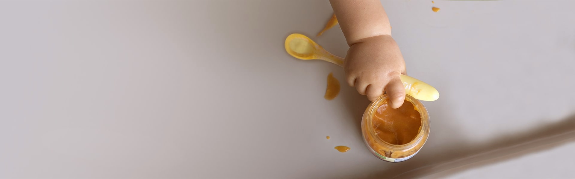 Baby greift Breischale mit einem Finger