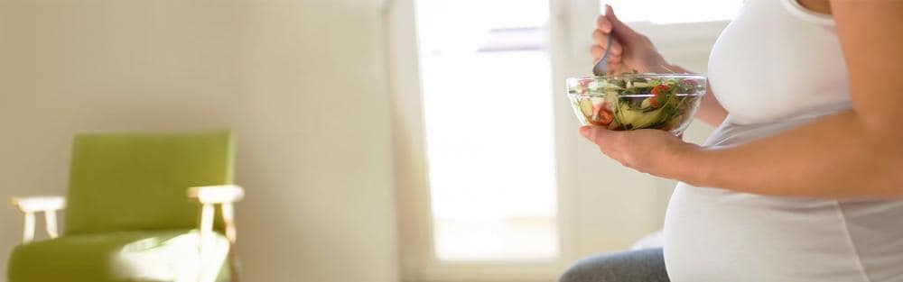 Une femme enceinte mange de la salade.