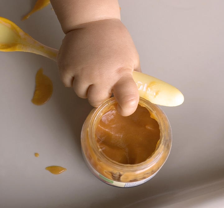 Baby greift Breischale mit einem Finger