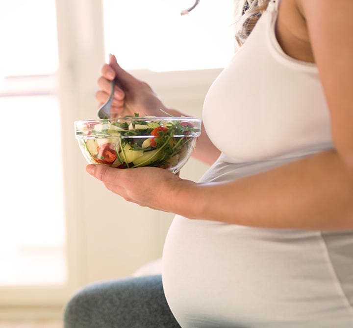 Schwangere Frau isst Salat